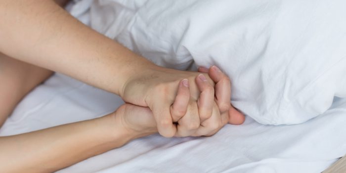 partial view of passionate lovers holding hands while making love on bed, banner,stock image